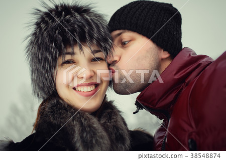 man and woman kissing in winter park 38548874