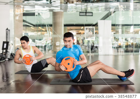 Determined young man exercising Russian twist Determined young man exercising Russian twist 38548877