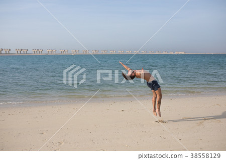 Young man doing somersault on the beach. Young man doing somersault on the beach. 38558129