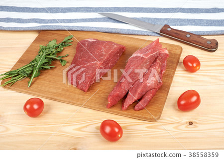 Sliced raw beef on cutting board and vegetables Sliced raw beef on cutting board and vegetables 38558359