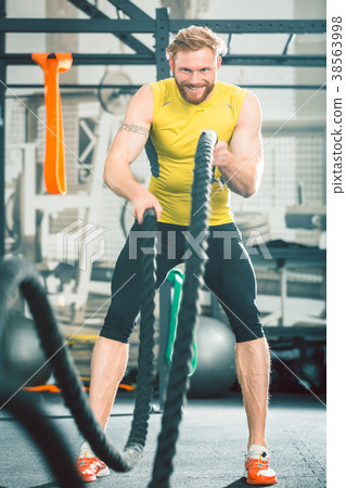 Handsome bodybuilder exercising with battle ropes Handsome bodybuilder exercising with battle ropes 38563998