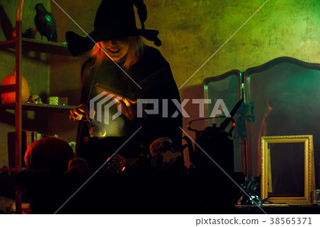 Image of witch in black hat reading spell over pot Image of witch in black hat reading spell over pot 38565371