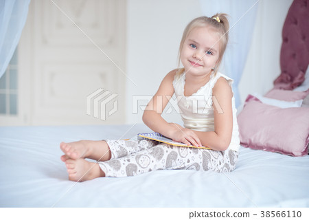 Cute little blond girl lying on bed Cute little blond girl lying on bed 38566110