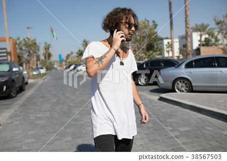 Man in a white T-shirt smokes and speaks on the Man in a white T-shirt smokes and speaks on the 38567503