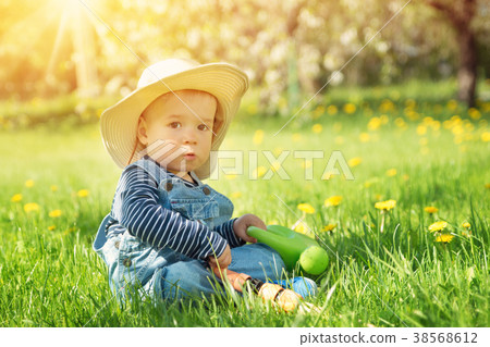 Baby boy sitting on the grass with dandelion 38568612