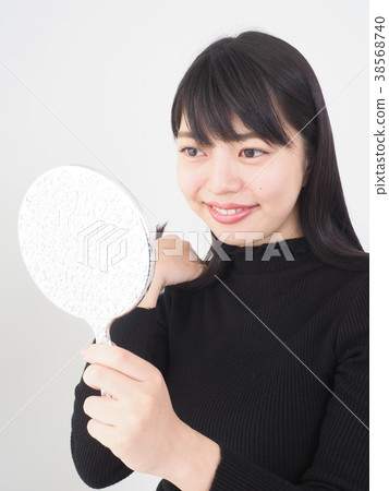 A woman looking at a mirror and smiling A woman looking at a mirror and smiling 38568740