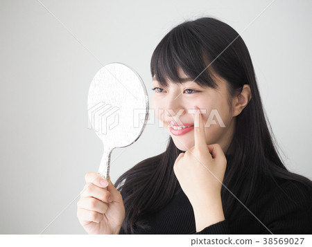 A woman looking at a mirror and smiling A woman looking at a mirror and smiling 38569027