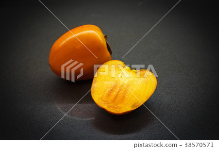 Delicious raw ripe persimmon fruit on dark 38570571