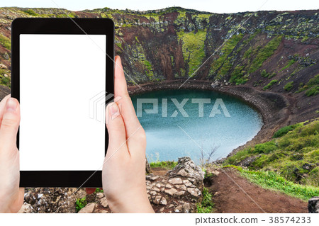 tourist photographs Kerid lake in volcanic crater 38574233
