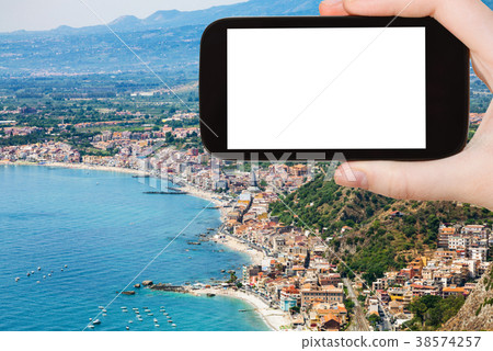 tourist photographs shore with Giardini Naxos 38574257