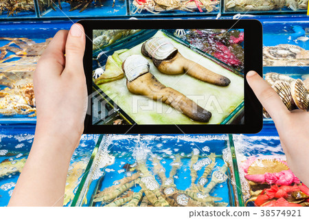 tourist photographs geoduck clams on fish market 38574921