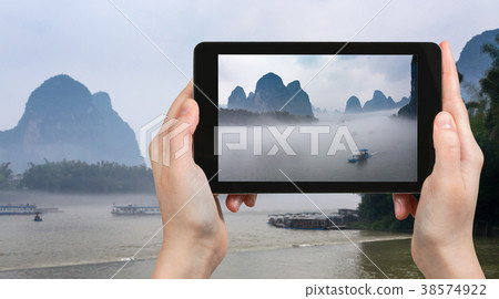 tourist photographs boat in mist on river in China 38574922