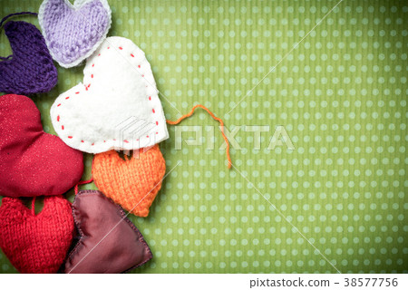 Colorful knitted hearts on a green background 38577756