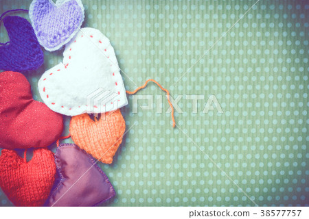 Colorful knitted hearts on a green background 38577757