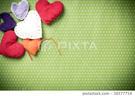 Colorful knitted hearts on a green background 38577759