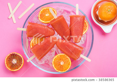 Orange juice healthy popsicles over ice cubes Orange juice healthy popsicles over ice cubes 38586365