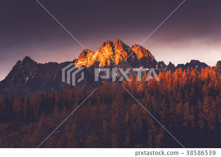 Last sun light hits high mountains peak at sunset Last sun light hits high mountains peak at sunset 38586539