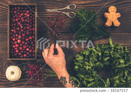 Tattooed florist hands making Christmas wreath Tattooed florist hands making Christmas wreath 38587557