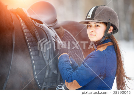 Young girl adjusting stirrups before riding horse Young girl adjusting stirrups before riding horse 38590045