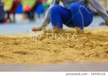 Sportsman landing into sandpit in long jump 38590126