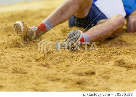 Sportsman landing into sandpit in long jump 38590128