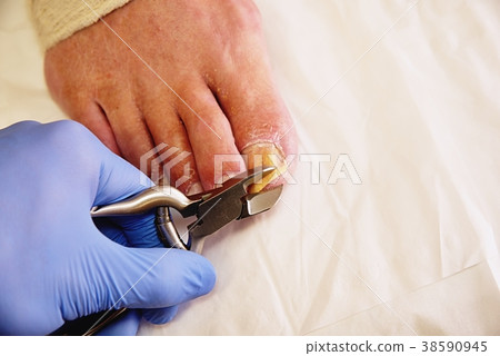 Close-up of a manicurist with pliers trimming 38590945