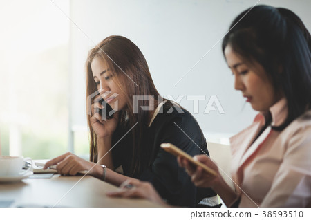 Young woman worker talking with smartphone in office Young woman worker talking with smartphone in office 38593510