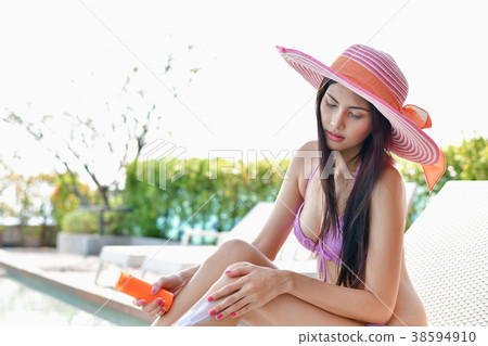 Swimsuit Concept. Beautiful girl in swimsuit is applying sunscre Swimsuit Concept. Beautiful girl in swimsuit is applying sunscre 38594910