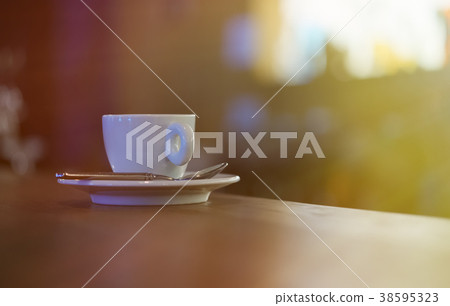 Cup of coffee with steam on table near window 38595323