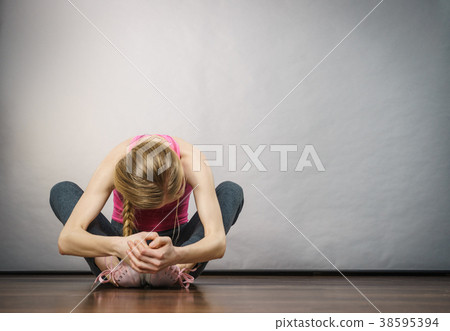 Sad depressed young teenage girl sitting by wall 38595394