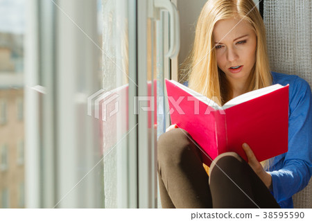 Woman reading on windowsill Woman reading on windowsill 38595590