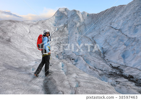 Woman climber standing in the cleft of the glacier 38597463