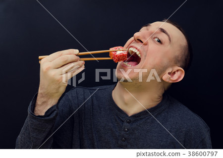 Man eats rolls with chopsticks. Open mouth Man eats rolls with chopsticks. Open mouth 38600797