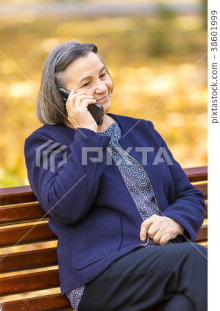 Senior woman talking on smartphone outdoors 38601999