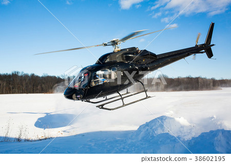 solo black helicopter in blue skies with snow 38602195