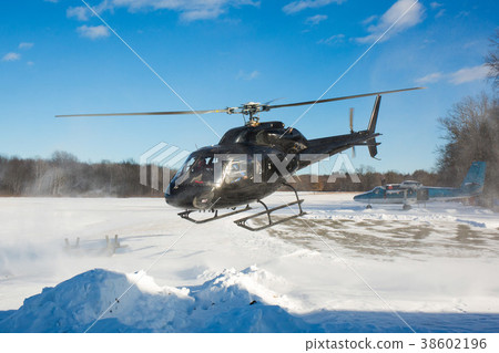 solo black helicopter in blue skies with snow 38602196