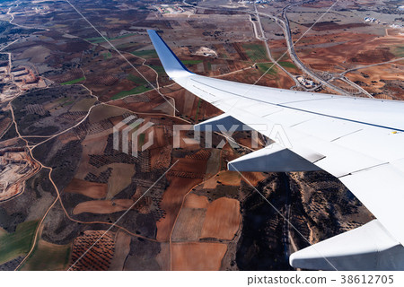 Wing of airplane above fields. 38612705