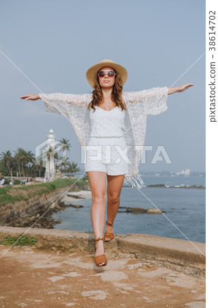 Girl in a hat with arms open on the ocean 38614702