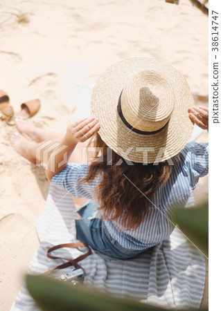 The girl from the back in the hat sits on the sand The girl from the back in the hat sits on the sand 38614747