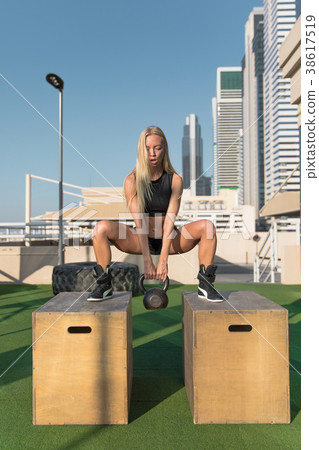 Young woman doing squats with kettlebell at gym. 38617519