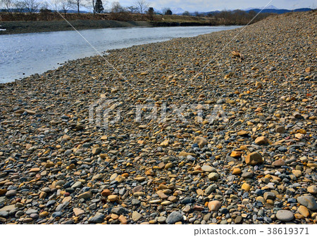 A gently flowing river surface and a wide pebble riverbank 38619371