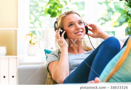 Happy young woman listening to music on headphones 38633326