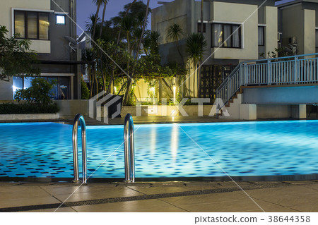 Pool at night with lush greenery and lighting Pool at night with lush greenery and lighting 38644358