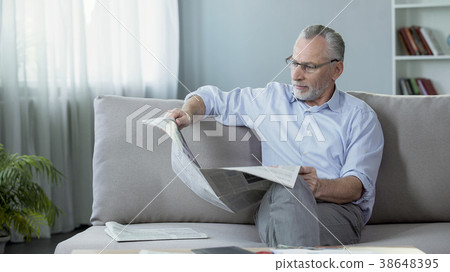 Man in his 60s sitting on couch and reading Man in his 60s sitting on couch and reading 38648395