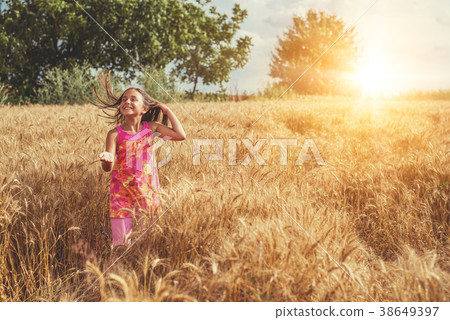 Happy little girl in a field of ripe wheat 38649397