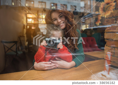 Cheerful daughter using photo camera near mother 38656182