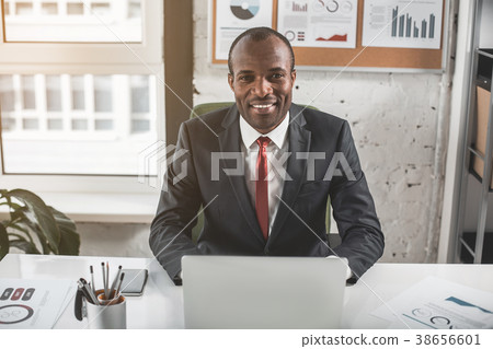 Positive stylish manager is laboring on notebook Positive stylish manager is laboring on notebook 38656601