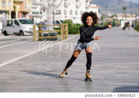 Black woman on roller skates riding outdoors on urban street Black woman on roller skates riding outdoors on urban street 38660825