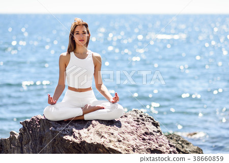 Young woman doing yoga in the beach wearing white clothes 38660859