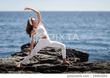 Young woman doing yoga in the beach wearing white clothes 38660860